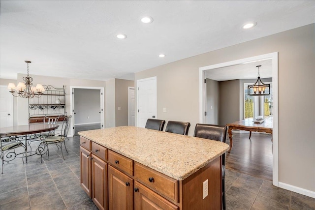 kitchen with pendant lighting, a kitchen island, a notable chandelier, and brown cabinets