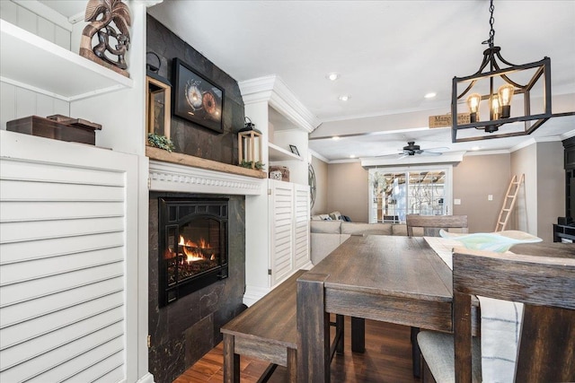 dining space with wood finished floors, a ceiling fan, recessed lighting, a glass covered fireplace, and crown molding