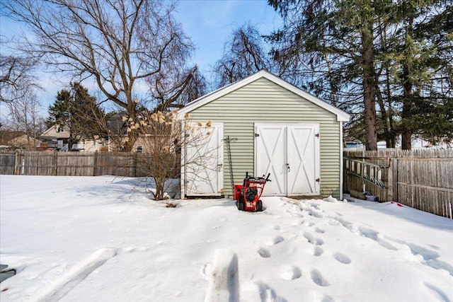 snow covered structure featuring an outdoor structure and fence