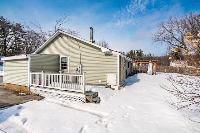 snow covered property featuring fence and a wooden deck