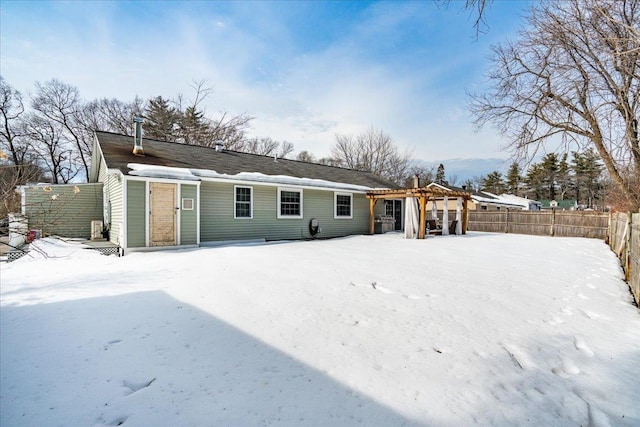 snow covered back of property with a pergola and fence