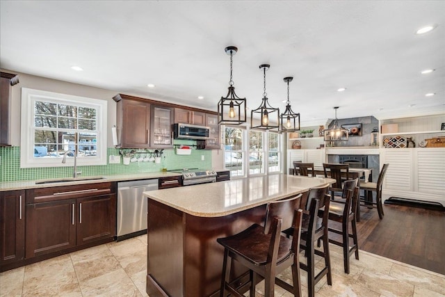 kitchen with decorative backsplash, appliances with stainless steel finishes, a kitchen bar, and a sink