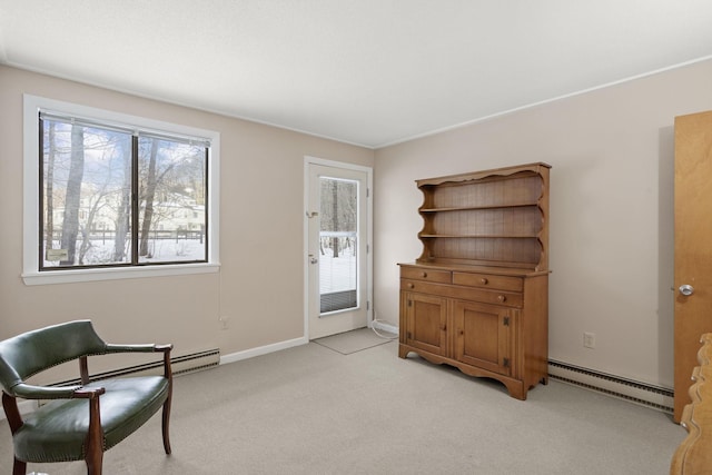 living area featuring baseboard heating, light colored carpet, and baseboards