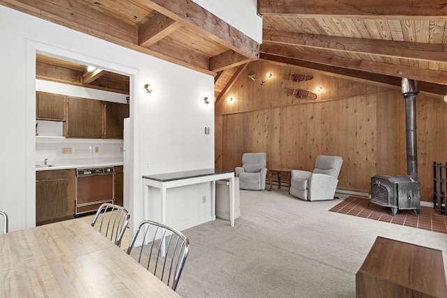 interior space featuring a wood stove, vaulted ceiling with beams, a sink, wood ceiling, and wood walls