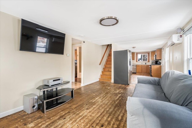 living area with an AC wall unit, stairs, baseboards, and wood finished floors