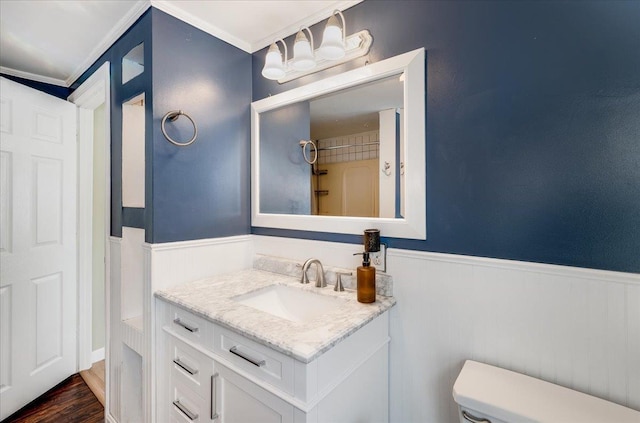 bathroom featuring vanity, toilet, wood finished floors, and wainscoting