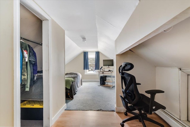 interior space with a baseboard heating unit, lofted ceiling, baseboards, and wood finished floors