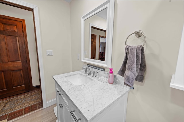 bathroom featuring baseboards, wood finished floors, and vanity