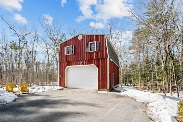 snow covered garage with a detached garage and aphalt driveway