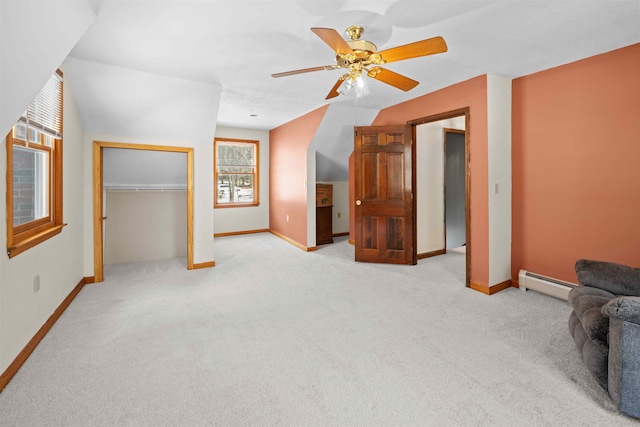 additional living space featuring a baseboard heating unit, a ceiling fan, baseboards, and light carpet