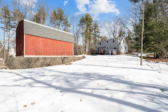 yard layered in snow featuring an outbuilding and a barn