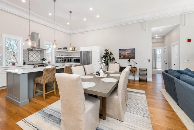 dining room featuring a wealth of natural light, light wood-style flooring, and a high ceiling