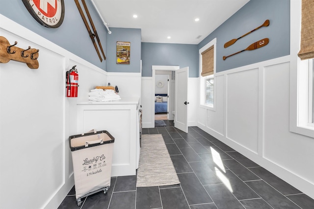 interior space with dark tile patterned flooring, a decorative wall, recessed lighting, and a wainscoted wall