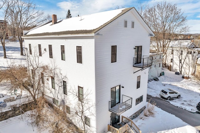 view of snow covered exterior with a chimney