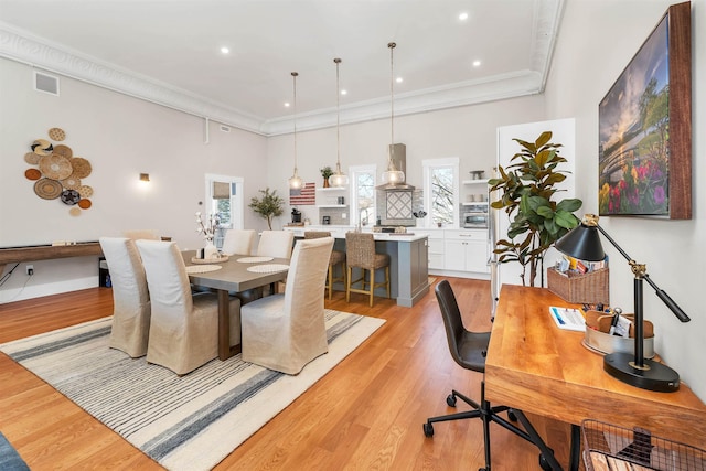 dining area featuring crown molding, plenty of natural light, visible vents, and light wood finished floors