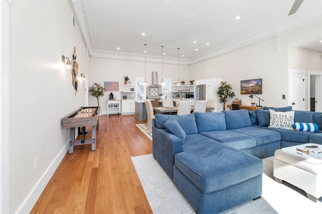 living room with recessed lighting, baseboards, light wood-style floors, and crown molding