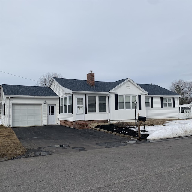 single story home with a chimney, driveway, an attached garage, and a shingled roof