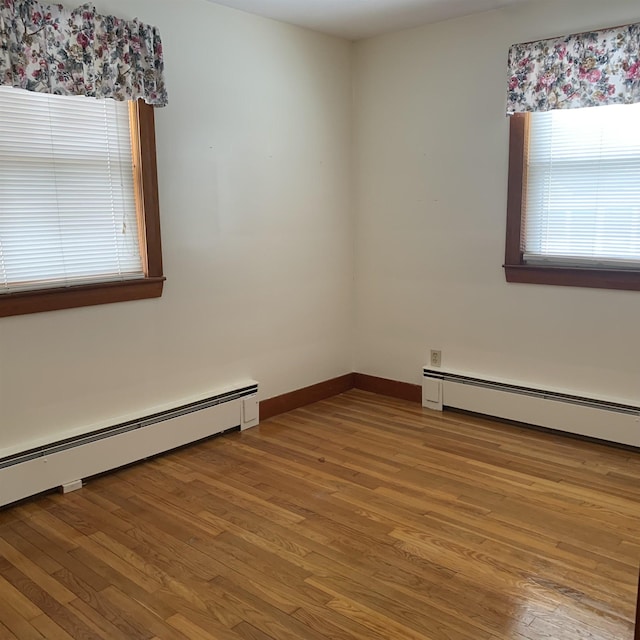 spare room with wood finished floors, baseboards, and a baseboard radiator