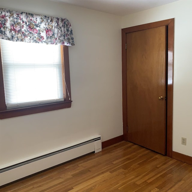 spare room featuring wood finished floors, baseboards, and a baseboard radiator