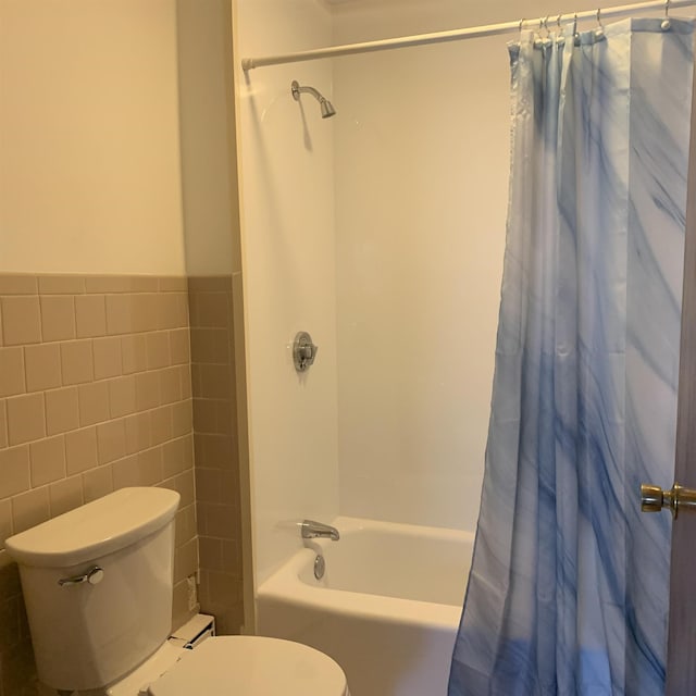 full bathroom featuring wainscoting, toilet, tile walls, and shower / bath combo with shower curtain