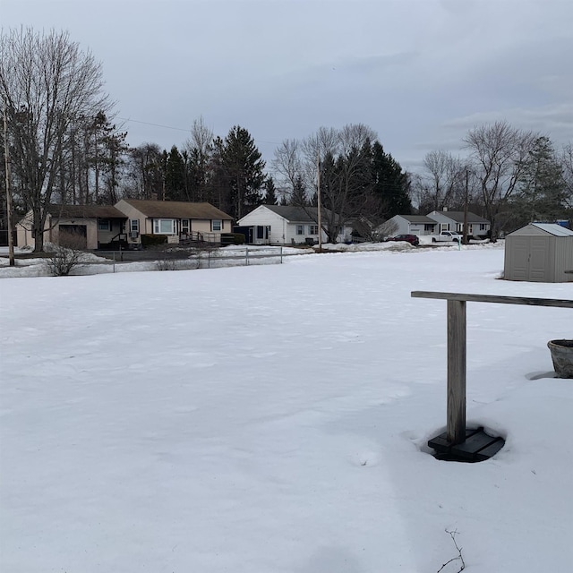 yard layered in snow featuring an outdoor structure, a garage, and a shed