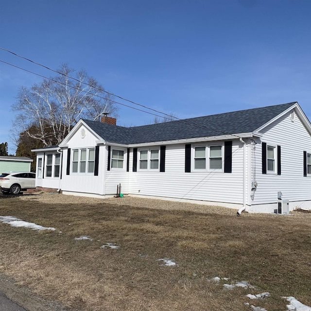 ranch-style house with a front yard, a chimney, and a shingled roof