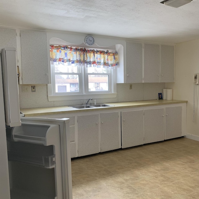 kitchen featuring a textured ceiling, light countertops, and a sink