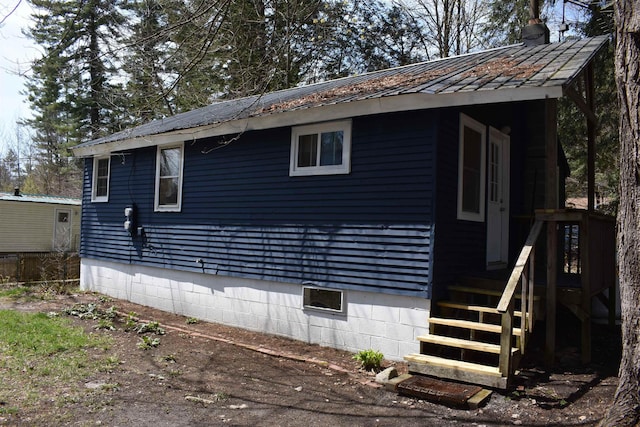 view of home's exterior featuring a chimney and metal roof