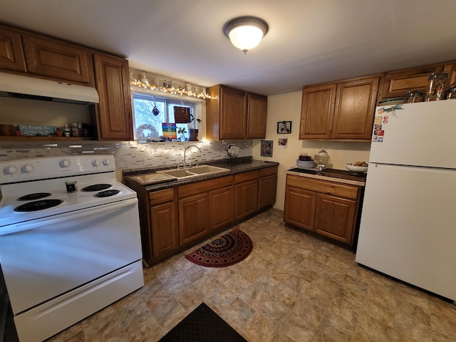 kitchen featuring under cabinet range hood, a sink, dark countertops, white appliances, and decorative backsplash