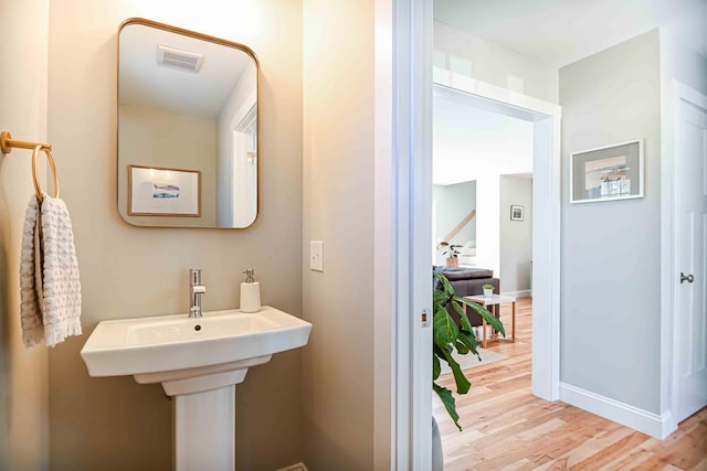 bathroom featuring visible vents, a sink, baseboards, and wood finished floors