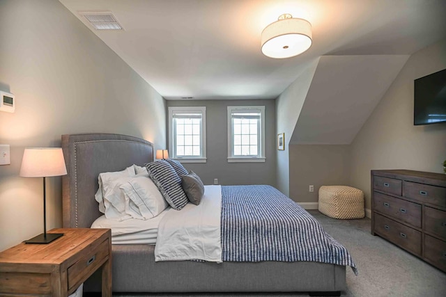 carpeted bedroom with lofted ceiling, baseboards, and visible vents