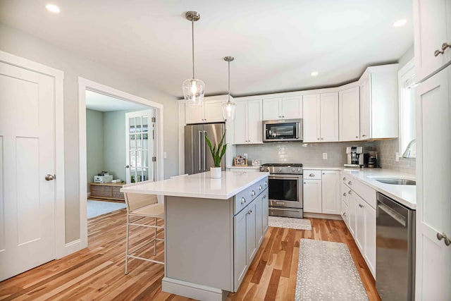 kitchen with a sink, premium appliances, tasteful backsplash, and light wood finished floors