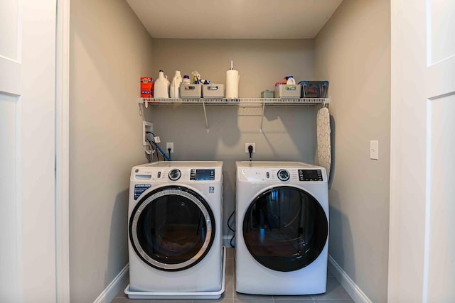 laundry area featuring washing machine and clothes dryer, laundry area, tile patterned floors, and baseboards