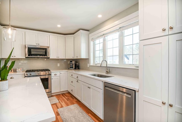 kitchen featuring a sink, stainless steel appliances, backsplash, and white cabinetry