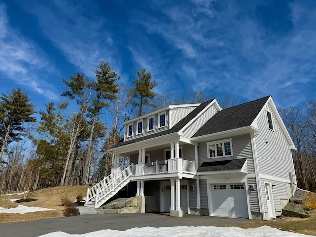 view of front of home featuring an attached garage, a porch, stairs, and a shingled roof