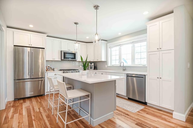 kitchen featuring a sink, white cabinetry, stainless steel appliances, light wood finished floors, and light countertops