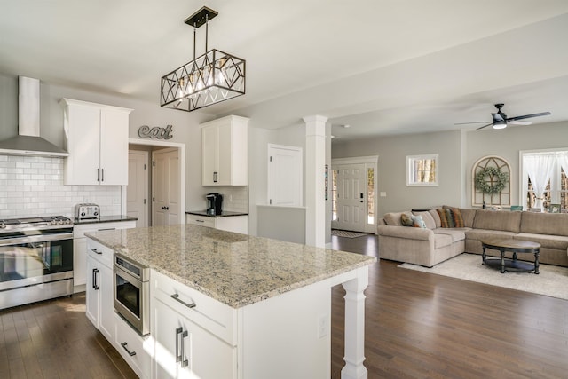 kitchen with light stone counters, open floor plan, stainless steel range with gas cooktop, wall chimney exhaust hood, and dark wood-style flooring