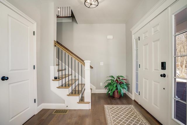 foyer entrance with visible vents, baseboards, wood finished floors, and stairs