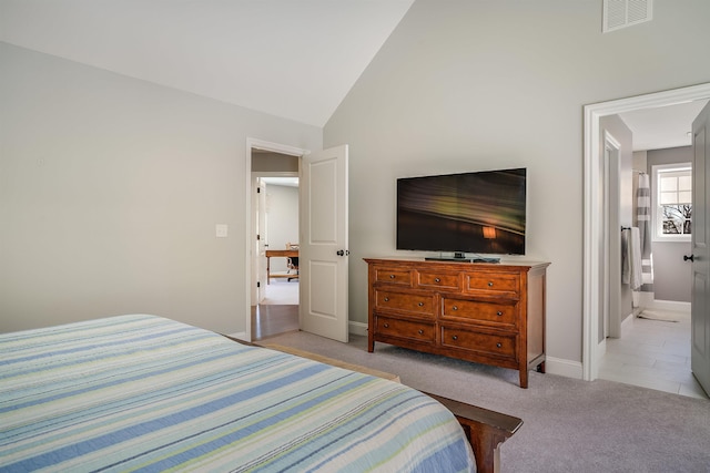 bedroom featuring visible vents, connected bathroom, baseboards, vaulted ceiling, and light carpet