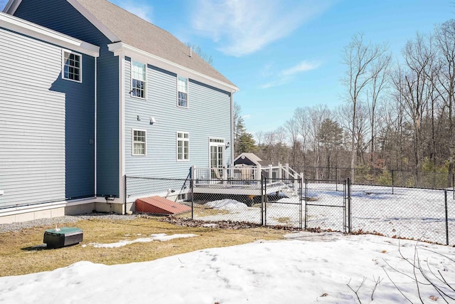 snow covered back of property featuring a gate, fence, and a wooden deck