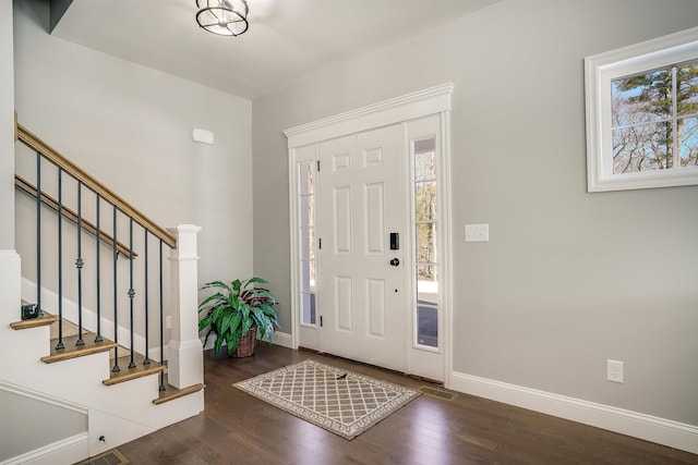 foyer entrance with stairway, baseboards, visible vents, and wood finished floors