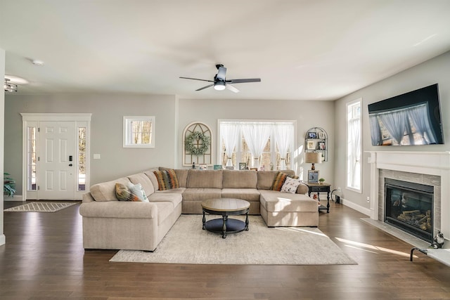 living area featuring dark wood finished floors, ceiling fan, a fireplace, and baseboards