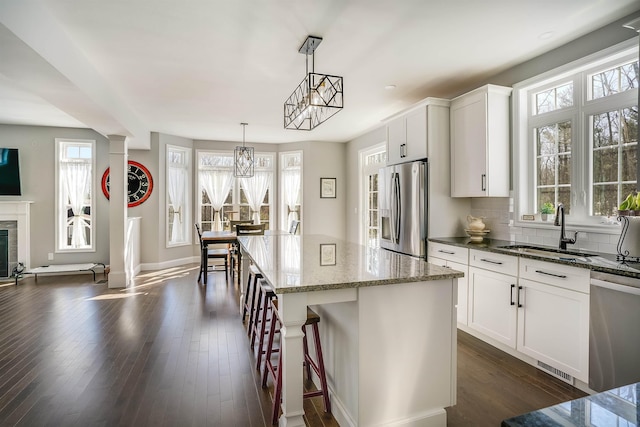 kitchen featuring dark wood-type flooring, a sink, tasteful backsplash, stainless steel appliances, and dark stone counters