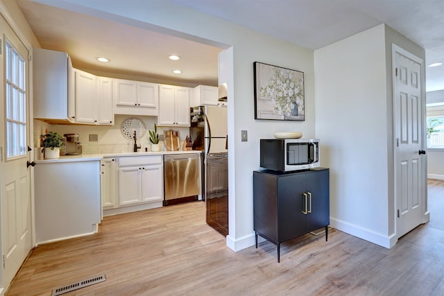 kitchen featuring visible vents, light wood-style flooring, white cabinets, and stainless steel appliances