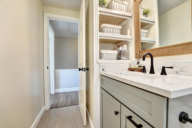 laundry room featuring baseboards, light wood finished floors, and a sink