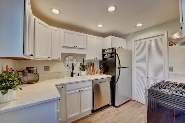 kitchen with light wood-type flooring, recessed lighting, white cabinets, stainless steel appliances, and a sink