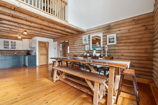 dining area with rustic walls, light wood-type flooring, and a towering ceiling