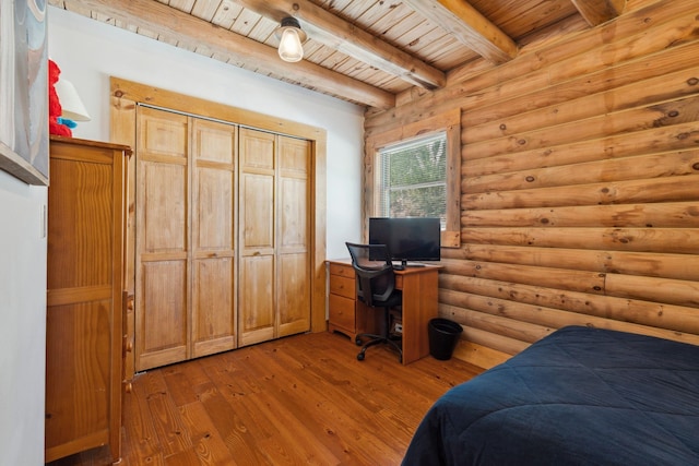 bedroom featuring rustic walls, beamed ceiling, wooden ceiling, and wood finished floors