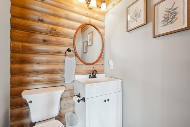 half bathroom featuring log walls, toilet, and vanity