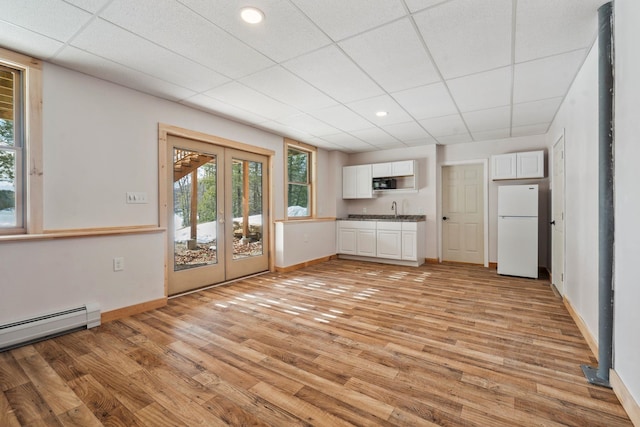 kitchen with white cabinets, plenty of natural light, light wood-style floors, and freestanding refrigerator